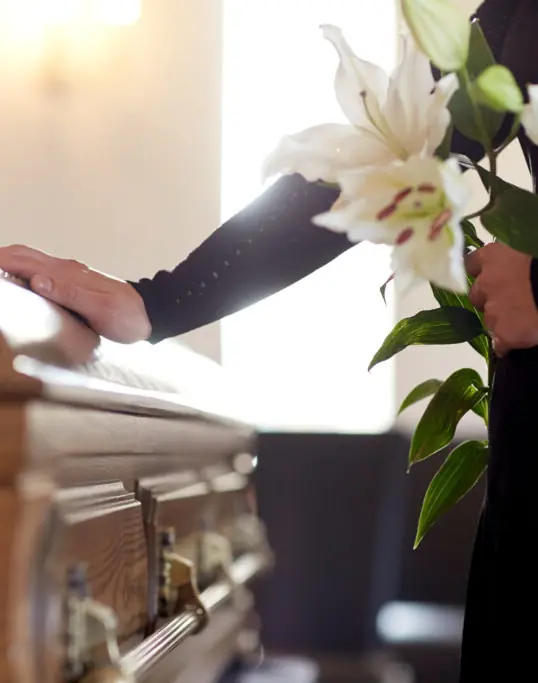 Woman with lilies and a coffin at a funeral
